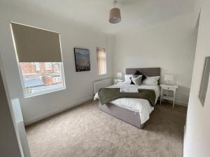 a white bedroom with a bed and a window at 4 bed 3 bedroom home near Middlesbrough centre in Middlesbrough