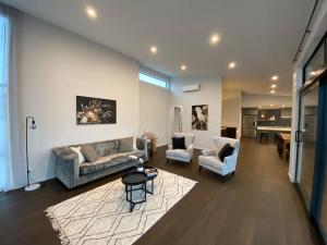 a living room with a couch and chairs and a table at Luxury Escape in CBD - entire brand new home in Tauranga