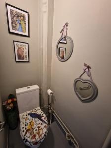 a bathroom with a toilet and some pictures on the wall at location chambre chez l'habitant in Épinay-sur-Seine