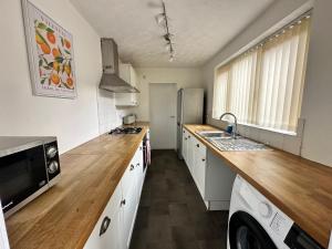 a kitchen with white cabinets and a wooden counter top at 4 bed 3 bedroom home near Middlesbrough centre in Middlesbrough