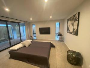 a bedroom with a large bed and a flat screen tv at Luxury Escape in CBD - entire brand new home in Tauranga