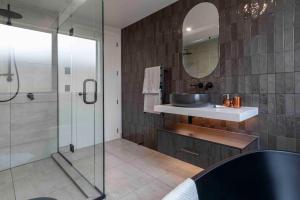 a bathroom with a sink and a glass shower at Luxury Escape in CBD - entire brand new home in Tauranga