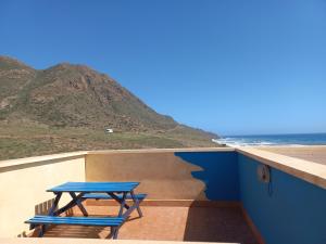 a picnic table sitting on a wall next to the beach at Casa La Fabriquilla en Cabo de Gata, Almería, Spain in Almería