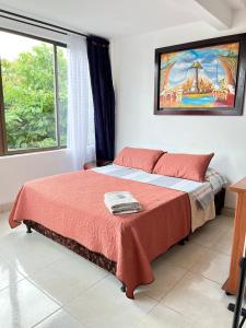 een slaapkamer met een bed met rode lakens en een raam bij Lindo Apartaestudio Centro Pereira in Pereira