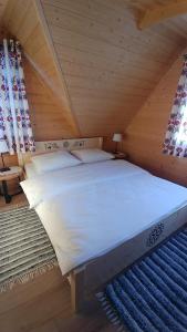 a bed in a wooden room with two windows at Domki Białka & Apartamenty in Białka Tatrzanska