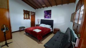 1 dormitorio con cama roja y sofá en Finca Hotel La Melania, en Montenegro