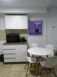 cocina con mesa blanca, sillas y microondas en Abasto 2062 en Rosario