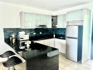 uma cozinha com um balcão preto e um frigorífico em Tropical Gardens Suites and Apartments em Coco