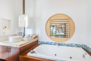 a bathroom with a tub and a sink and a mirror at Maia Suites Cozumel in Cozumel