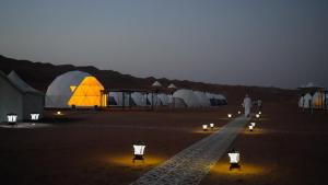 um grupo de tendas e luzes no deserto à noite em Luxury Desert Camp em Al Wāşil