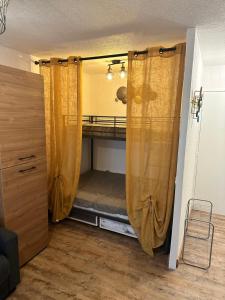 a closet with curtains and a bed in a room at T2 tout équipé floralie 2 in Le Grau-du-Roi