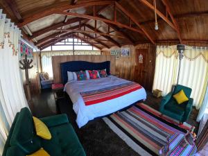 a bedroom with a bed and two chairs in a room at Pachamama Titicaca Lodge in Puno