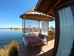a bed on a porch with an umbrella on the water at Pachamama Titicaca Lodge in Puno