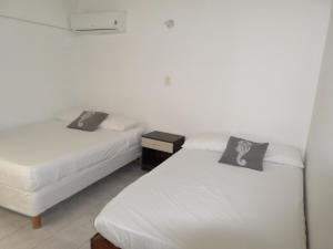 two beds in a room with white walls at Apartamento North Wind in San Andrés