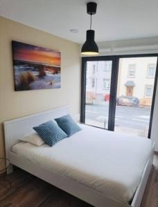 1 dormitorio con 1 cama blanca y 2 almohadas azules en New One bedroom Flat- Terrace & Parking, en Luxemburgo