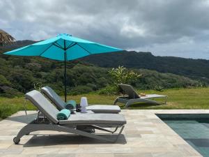 a blue umbrella and two lounge chairs and a table at La Suite Vue Lagon in Uturoa