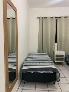 una camera da letto con specchio accanto a un letto di Apartamento aconchegante - Enseada - Guarujá a Guarujá
