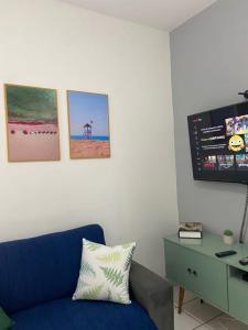 a living room with a blue couch and pictures on the wall at Apartamento aconchegante - Enseada - Guarujá in Guarujá