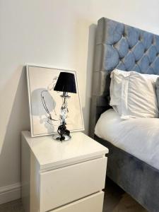 een lamp op een nachtkastje naast een bed bij Modern and spacious flat in Longbridge