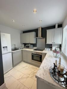 een keuken met witte apparatuur en een marmeren aanrecht bij Modern and spacious flat in Longbridge