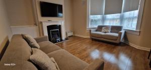 a living room with a couch and a chair at Archillects - Entire Two Bedroom Comfy House in Glasgow