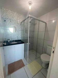 a bathroom with a toilet and a glass shower at Apto com Ar com vista para praia de Morro Branco - Fortaleza in Beberibe