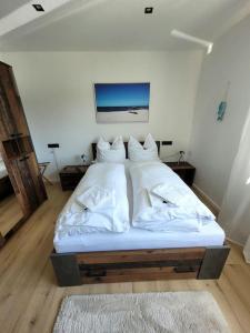 Bett in einem Zimmer mit weißer Bettwäsche und Kissen in der Unterkunft Exklusive Dorfpension mit Pool und Sauna in Lage