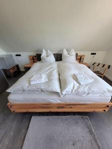 a bed with white sheets and pillows on it at Exklusive Dorfpension mit Pool und Sauna in Lage