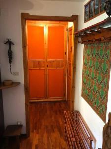 - un couloir avec une porte orange et un banc dans une chambre dans l'établissement Un nido accogliente con vista, à Verrand