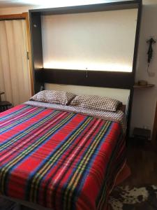 - un lit avec une couverture colorée dans l'établissement Un nido accogliente con vista, à Verrand