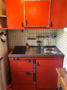 - une cuisine avec des placards rouges et un évier dans l'établissement Un nido accogliente con vista, à Verrand