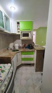 a kitchen with green cabinets and a microwave at Apartamento 2 suítes Frente à Praia de Camboinhas - Niterói - RJ - Brasil in Niterói