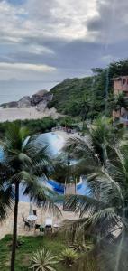 a view of a beach with palm trees and chairs at Apartamento 2 suítes Frente à Praia de Camboinhas - Niterói - RJ - Brasil in Niterói