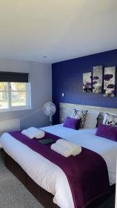 2 große Betten in einem Schlafzimmer mit lila Wänden in der Unterkunft The Woolpack Inn in Kettering