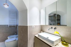 Un baño con lavabo, inodoro y espejo. en [Navigli-Duomo] Sweet22 Luxury OpenSpace, en Milán 11 fotos más