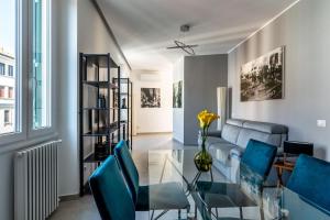 Una sala de estar con una mesa de cristal y sillas azules. en [Navigli-Duomo] Sweet22 Luxury OpenSpace, en Milán