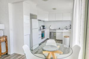 cocina con mesa de cristal y electrodomésticos blancos en The Blue Whale - Sea View Apartment, en Eden