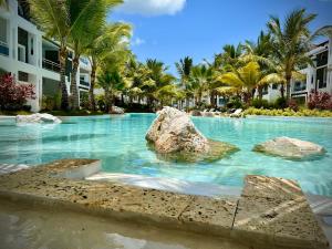 a swimming pool with a rock in the water at Komfortowy Apartament z 4 Basenami i Pięknym Ogrodem, Estrella Dominicus-Bayahibe in Bayahibe