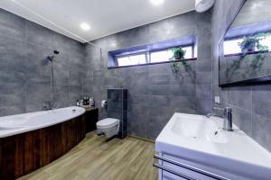 a bathroom with a tub and a toilet and a sink at Metal-House in Vievis