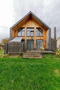 Metal-House في Vievis: منزل خشبي صغير مع سور واعشاب خضراء
