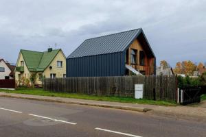 Metal-House في Vievis: منزل بسقف أسود وسياج