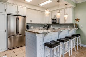 a kitchen with white cabinets and a stainless steel refrigerator at Dauphin Island Beach Club 106A in Dauphin Island