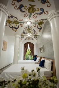 a bedroom with two beds and a ceiling with paintings at HELLO VILLA & SPA in Hue