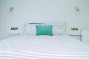 a white bed with a green pillow on it at The Hideout in Newry