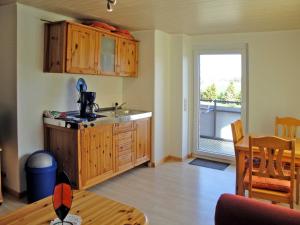 eine Küche mit Holzschränken, einem Tisch und einem Fenster in der Unterkunft Ferienwohnungen Fleesensee in Malchow