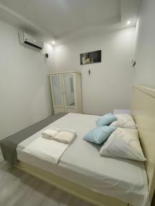 Schlafzimmer mit einem Bett mit weißer Bettwäsche und blauen Kissen in der Unterkunft City Appartementen New Nickerie - 4-6p in Nieuw Nickerie