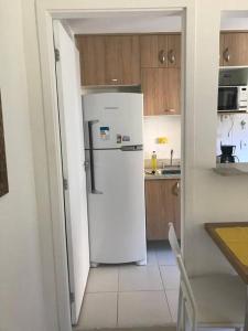 a white refrigerator in a kitchen with wooden cabinets at Loft no Condomínio Reserva do Sahy + Piscina in Mangaratiba