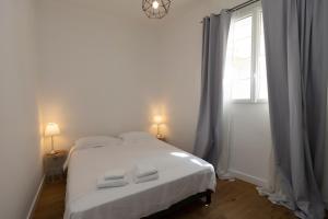 ein Schlafzimmer mit einem weißen Bett und einem Fenster in der Unterkunft Les Suites R Bonaparte - Appartements de standing au cœur de la vieille ville piétonne in Ajaccio
