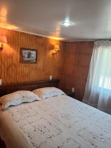 a bedroom with a bed with two pillows and a window at Apartamentos Cadiz -Valdivia in Valdivia