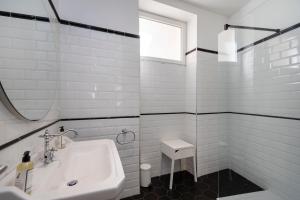 ein weißes Badezimmer mit Waschbecken und Spiegel in der Unterkunft Les Suites R Bonaparte - Appartements de standing au cœur de la vieille ville piétonne in Ajaccio + 14 Fotos